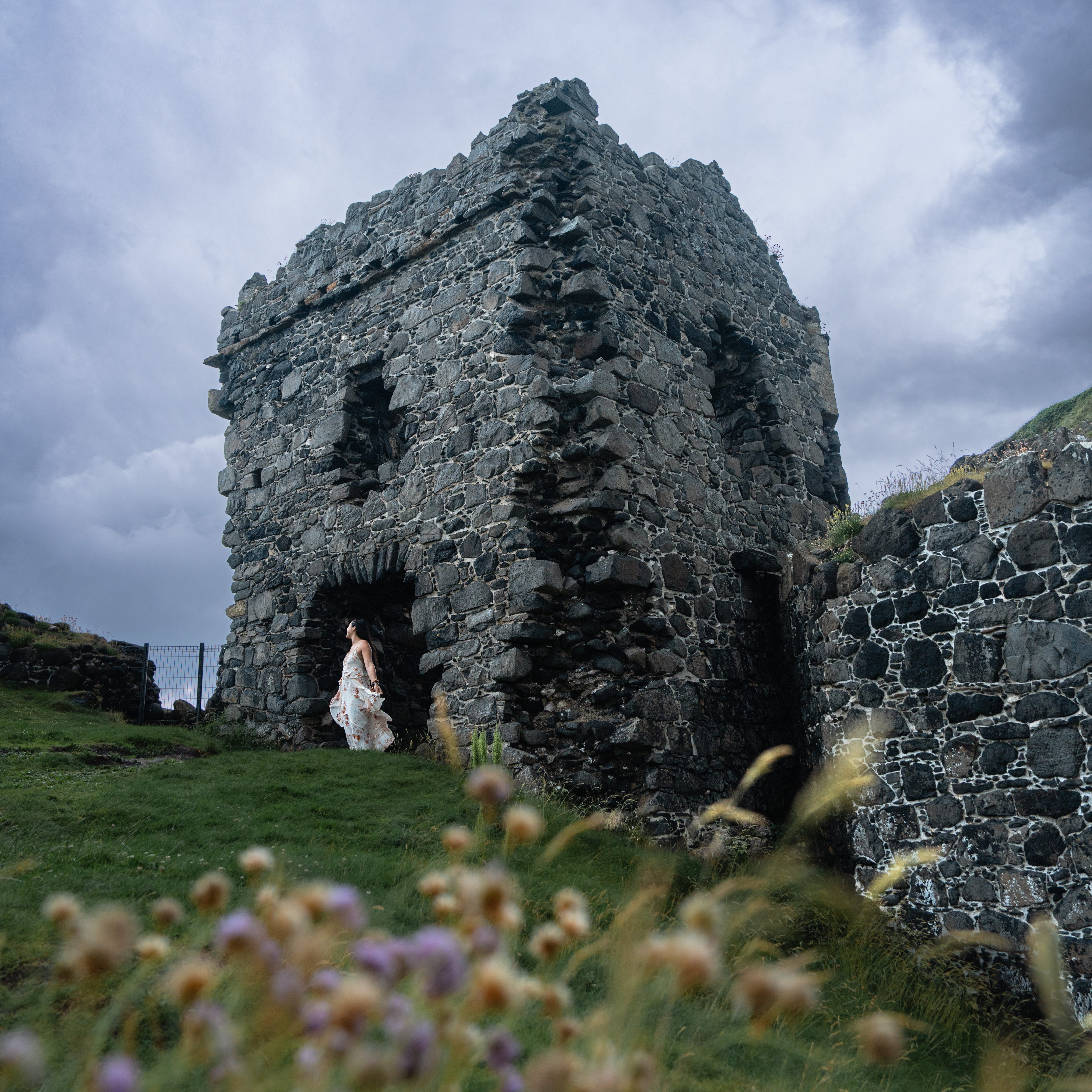 Lauren wearing a white dress, standing in front of kinbane castle on northern ireland's causeway coast.